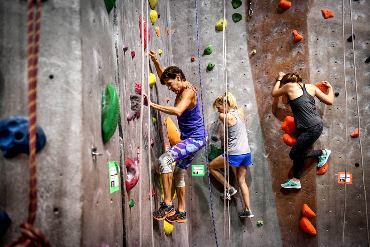Climbers training on an indoor climbing wall, one wearing knee supports